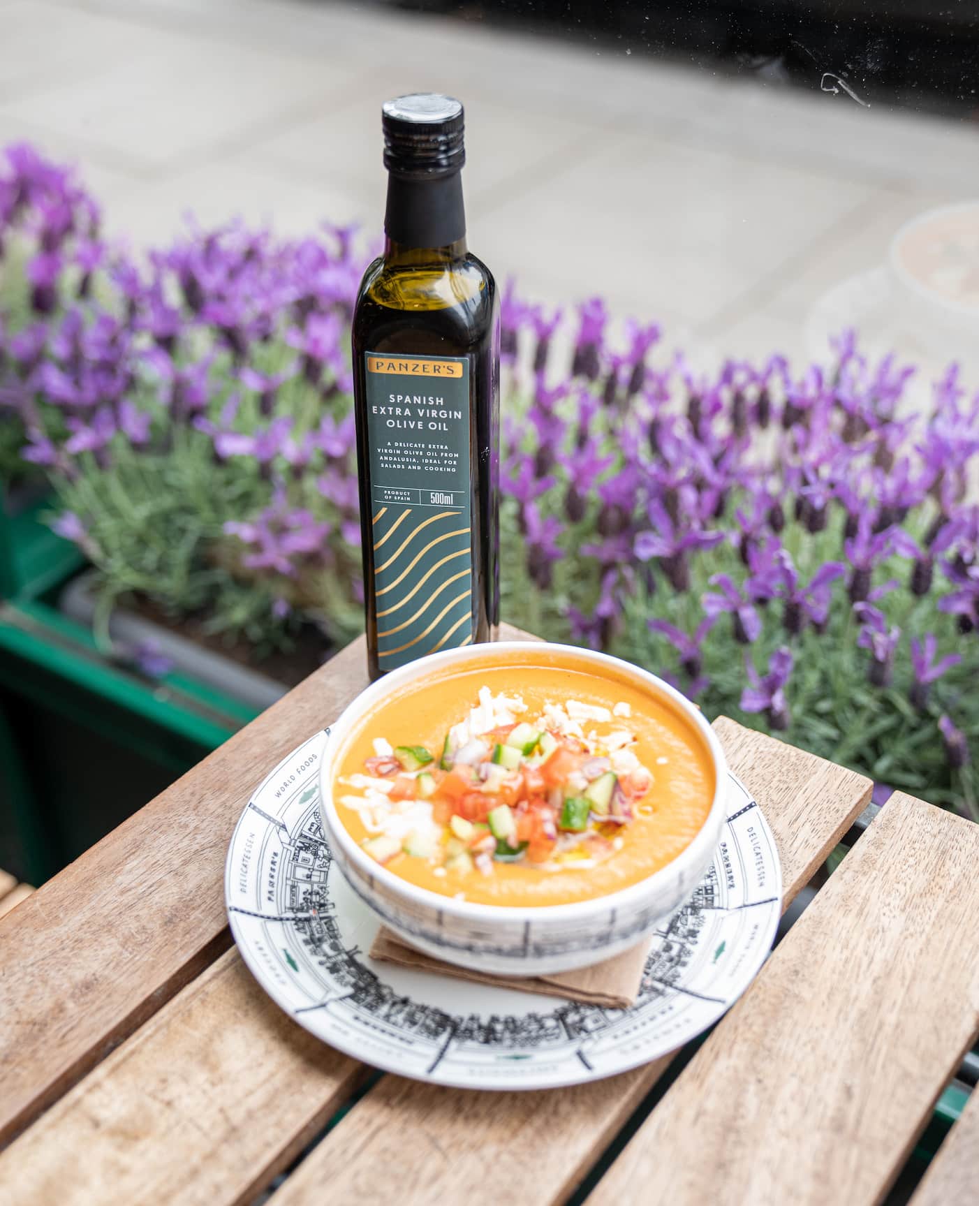 A bowl of Panzer's homemade gazpacho with a bottle of Panzer's olive oil perched behind it