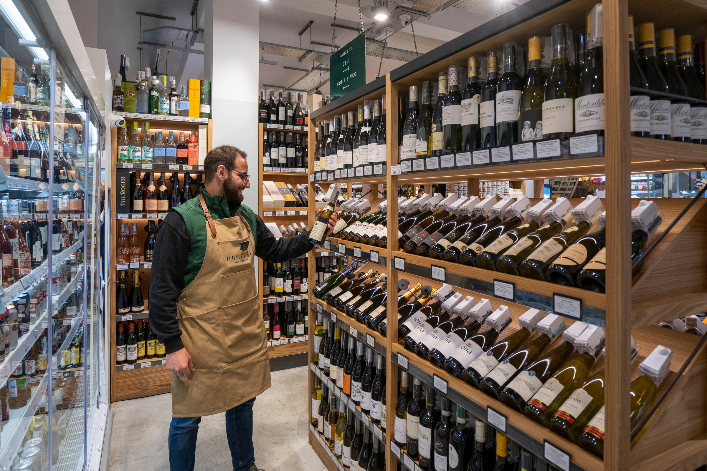 A member of staff stands in front of Panzer's deli wine ranks