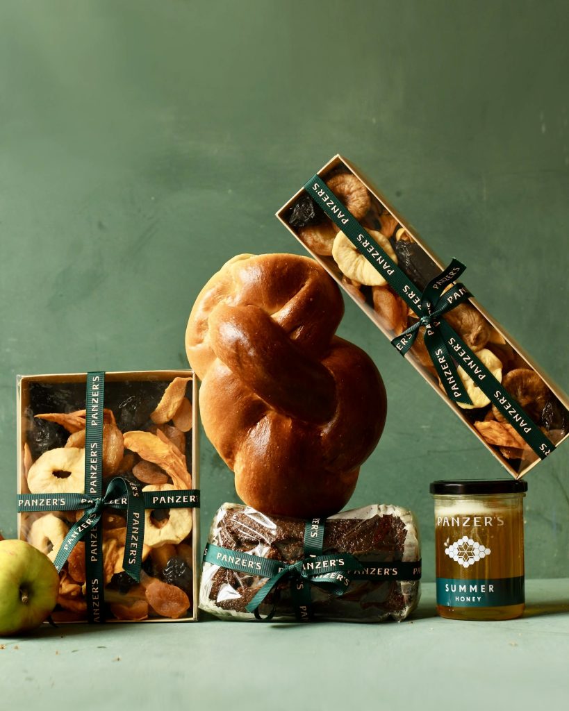 Rosh Hashanah spread of Panzer's products, including challah, pomegranates, their four generation recipe Honey Cake, fried fruit and apples to dip in honey